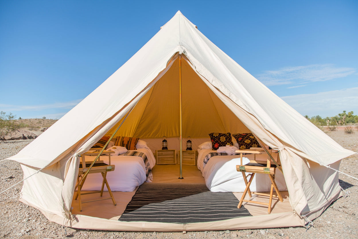 Large beige bell tent with interior furniture in a desert setting
