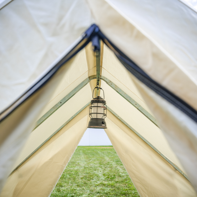 Tent interior with a hanging lantern and view of grass outside