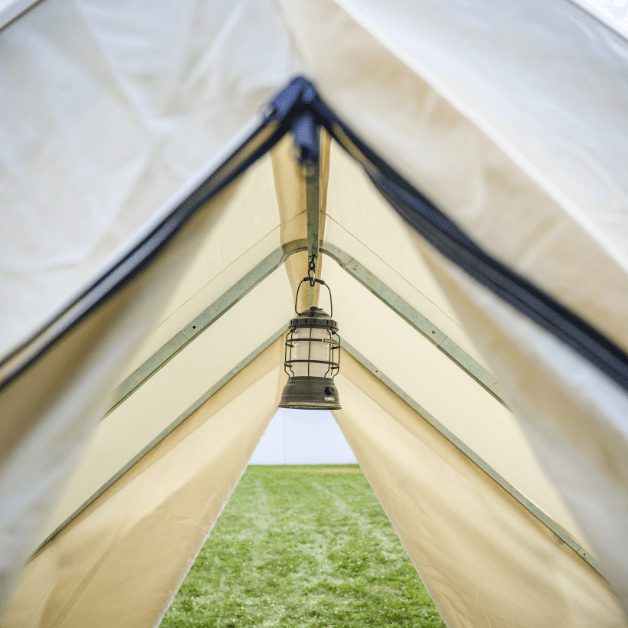 Tent interior with a hanging lantern and view of grass outside