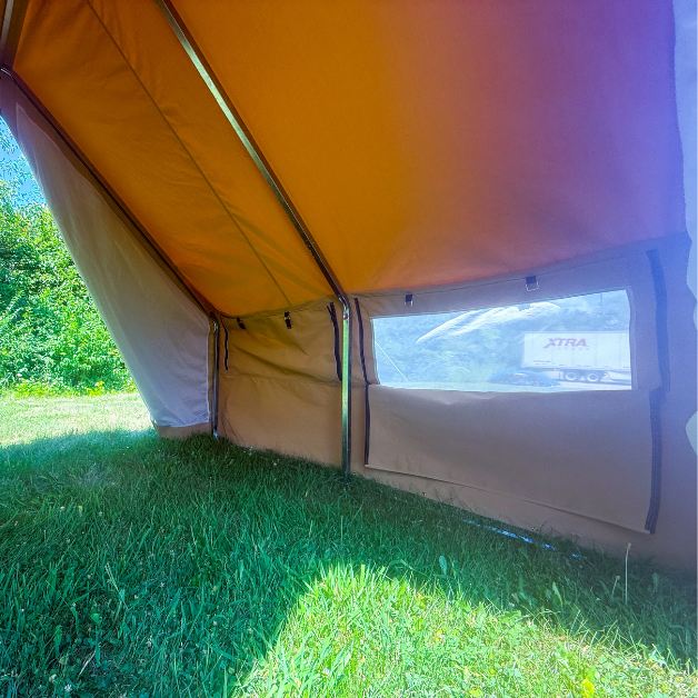 Beige tent with window on grass with trees in background
