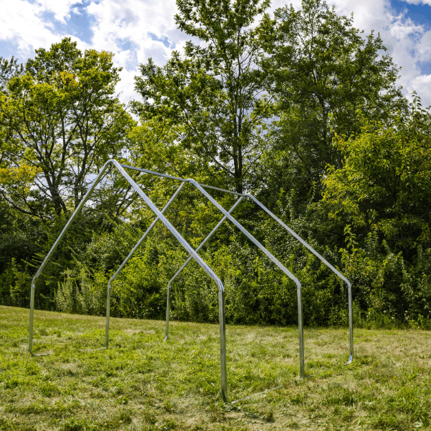 Metal tent frame structure on grass with trees in the background