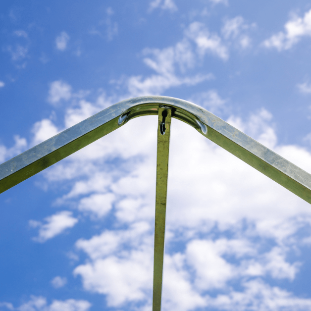Metal wall tent frame against a blue sky with clouds