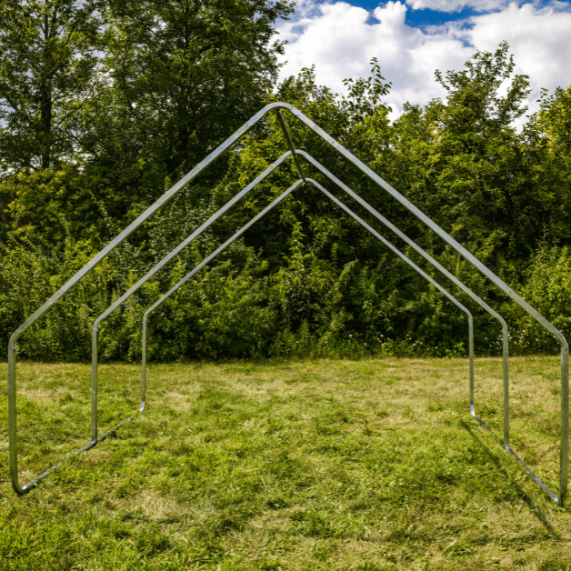 Metal wall tent frame on a grassy field with trees in the background