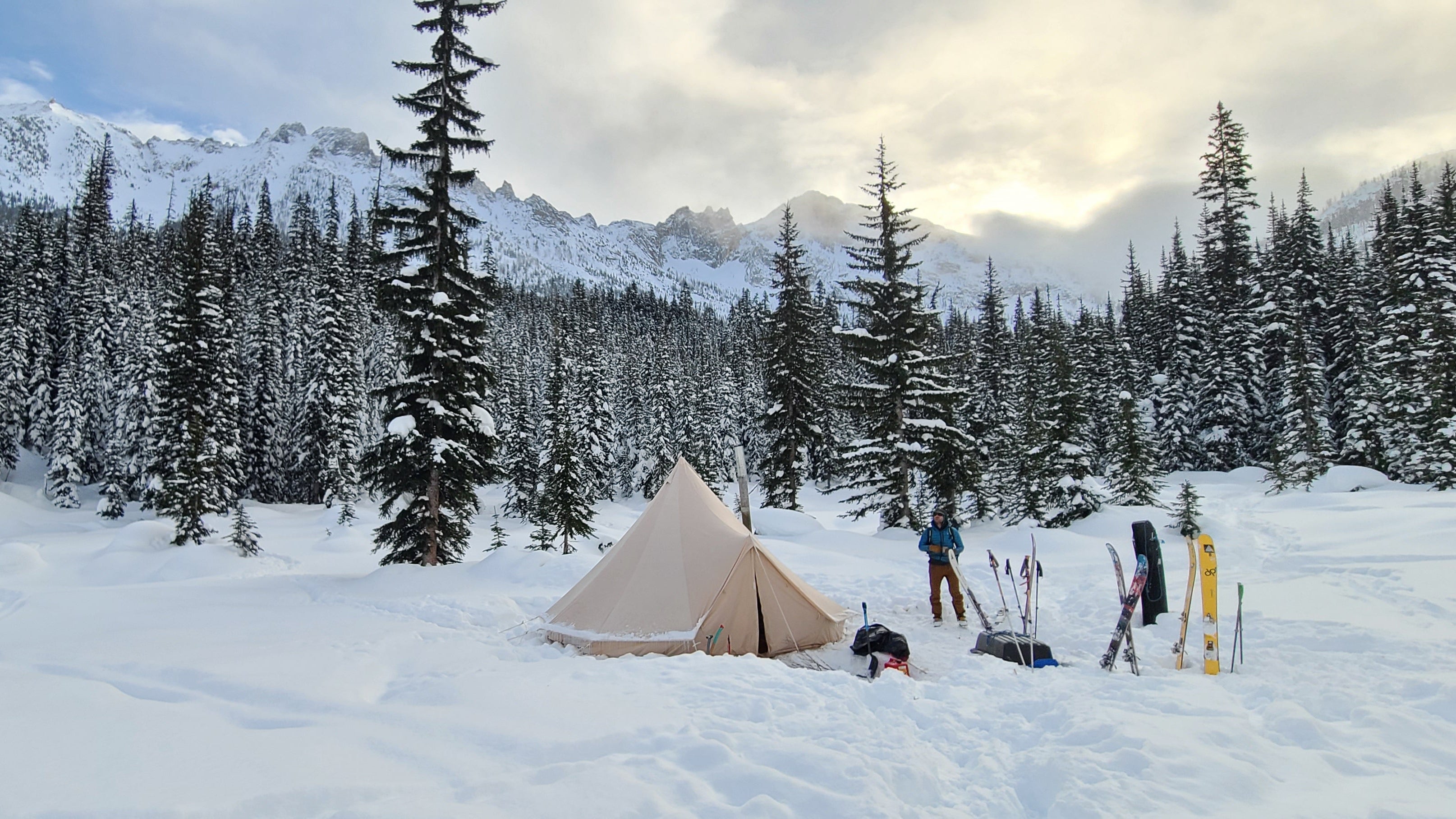Tent in a snowy landscape with mountains and trees in the background