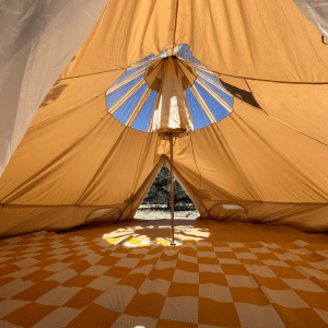 Inside view of a beige tent with a yellow checkered rug