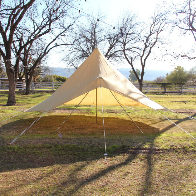 Beige tent awning set up on a grassy field with trees in the background