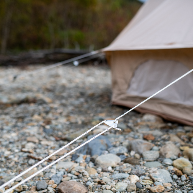 Tent setup on a rocky ground with a blurred natural background