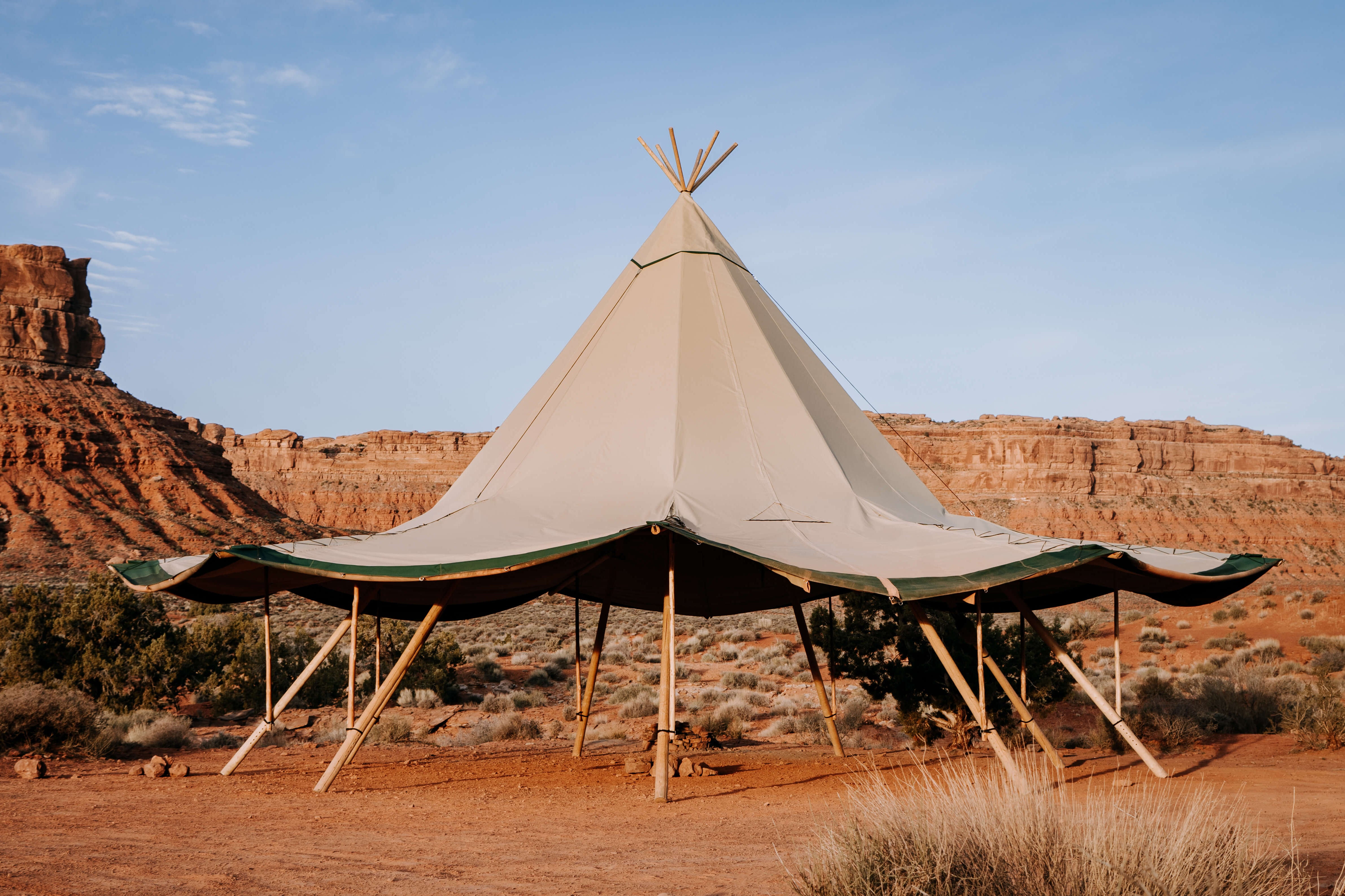 Tipi-style tent in a desert landscape with rocky formations and clear sky