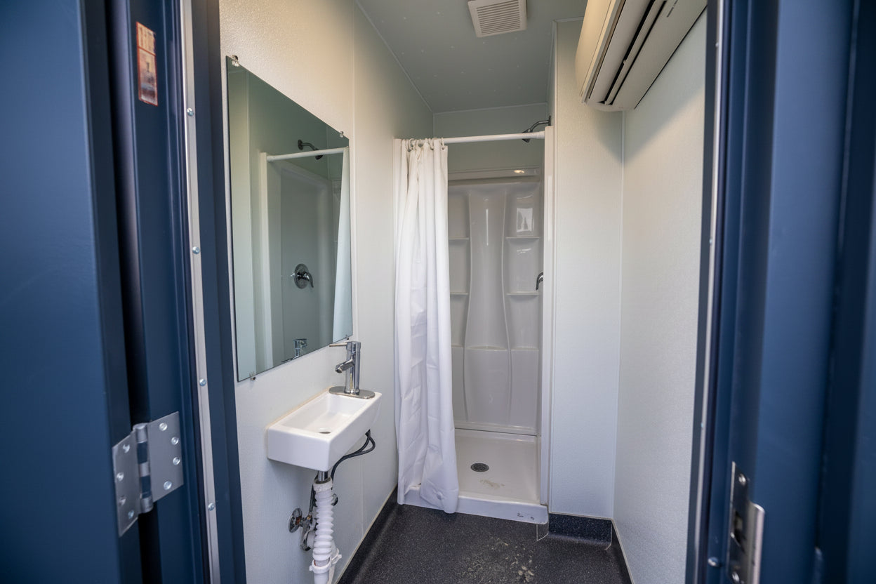 Bathroom with sink, mirror, and shower stall inside a blue door.