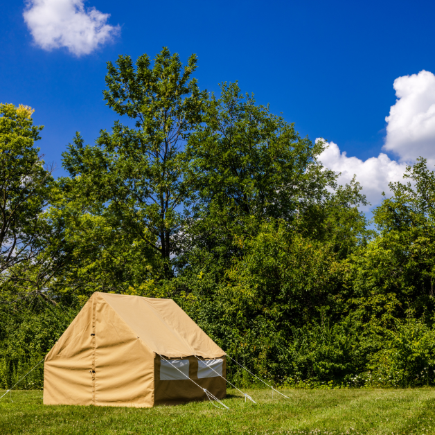 Beige wall tent in a grassy area with trees and blue sky