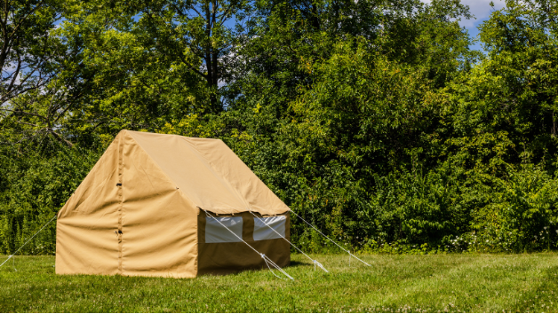 Beige wall tent in a grassy area with trees and blue sky