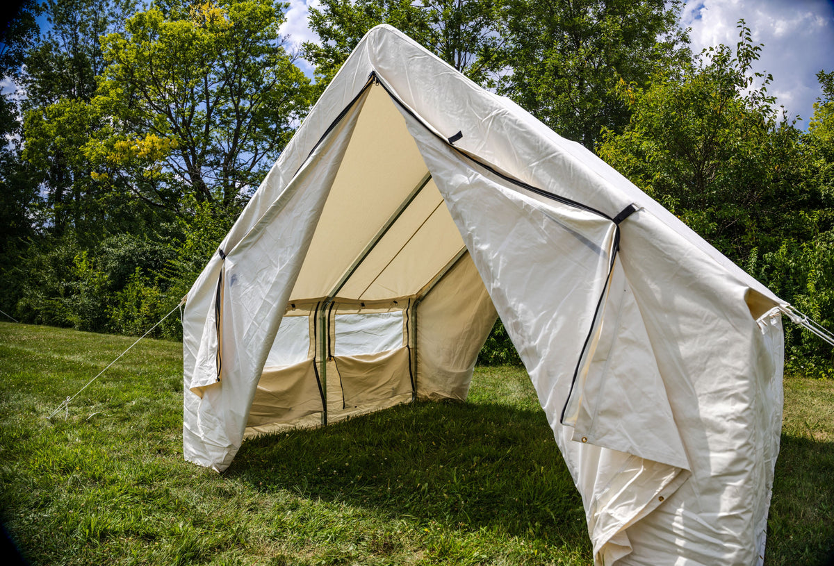 Beige bell tent with white flysheet on grassy area with trees in the background