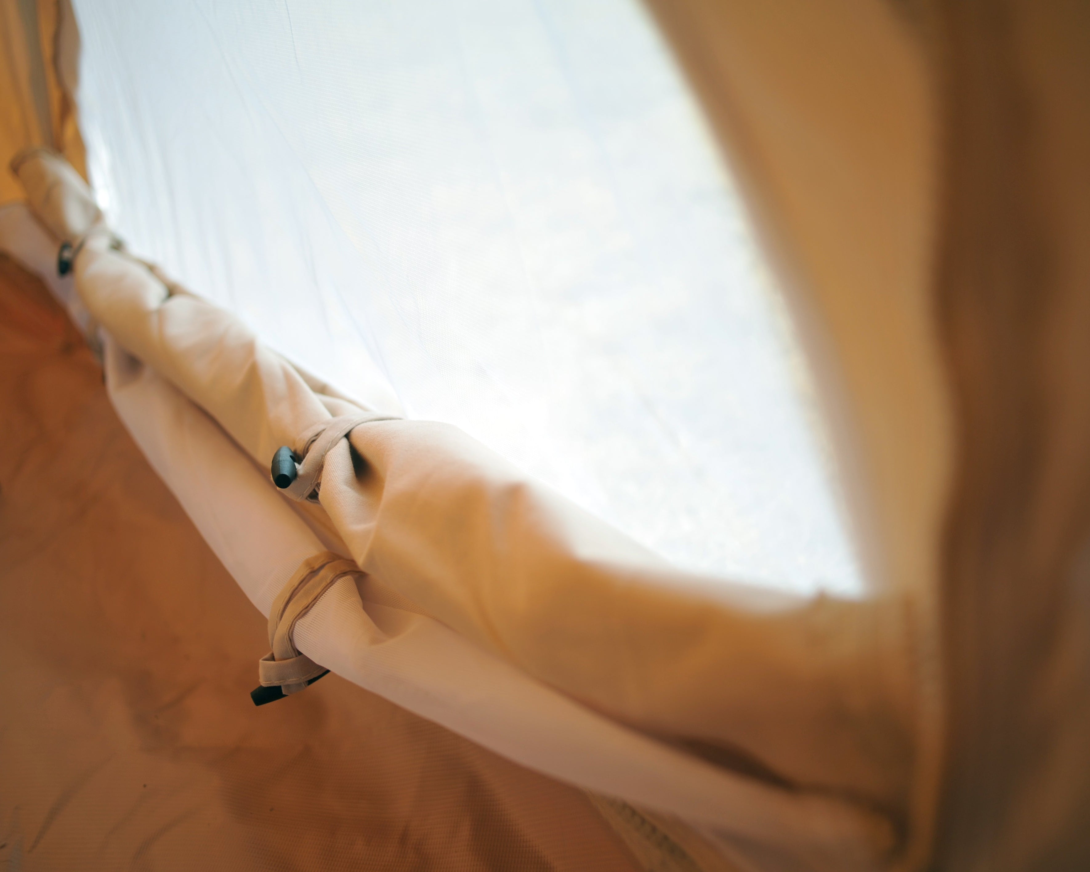 Partial view of a beige inflatable structure with a bright light source in the background