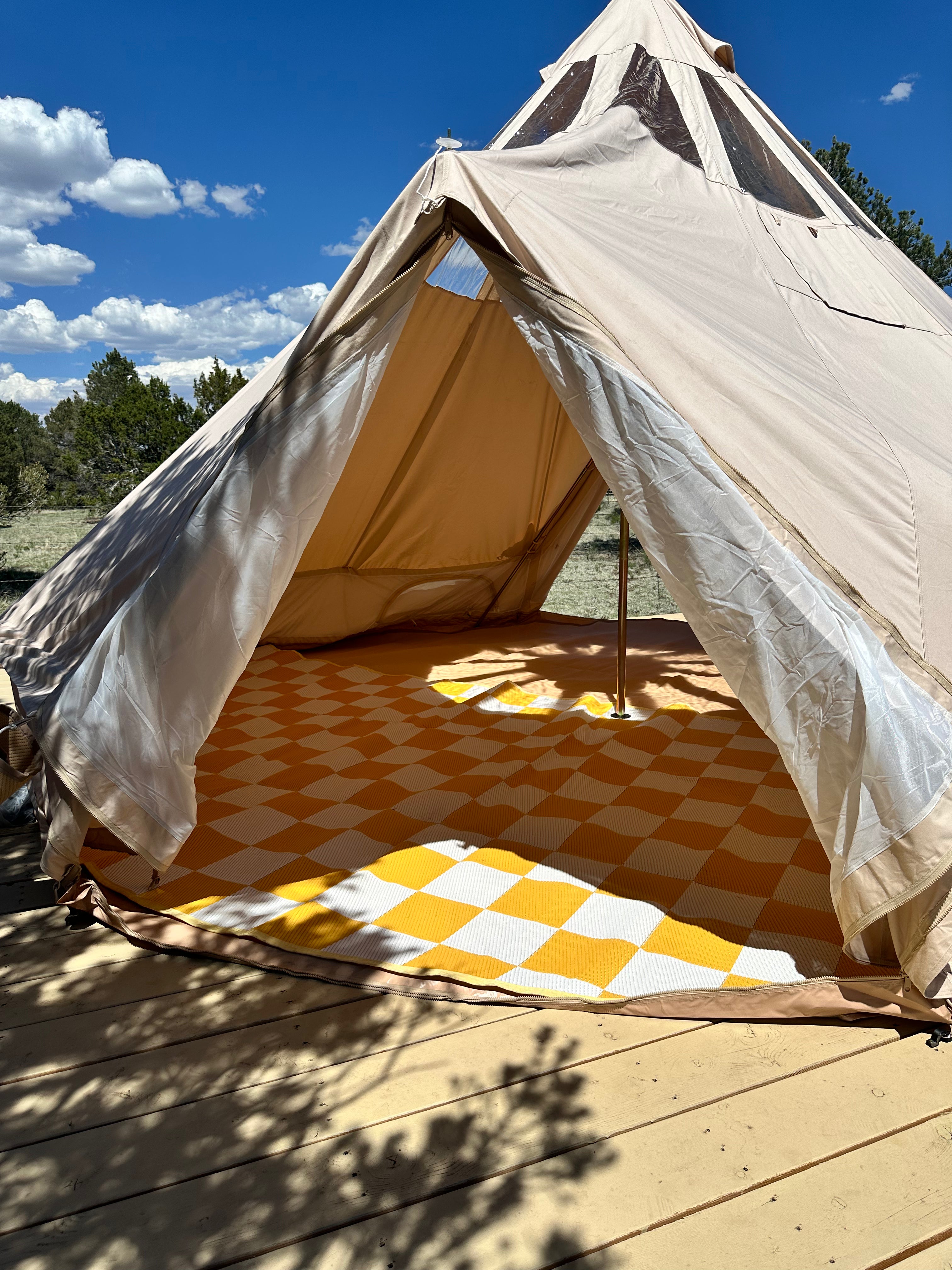 Tent with ceiling windows with a yellow checkered floor in a natural setting