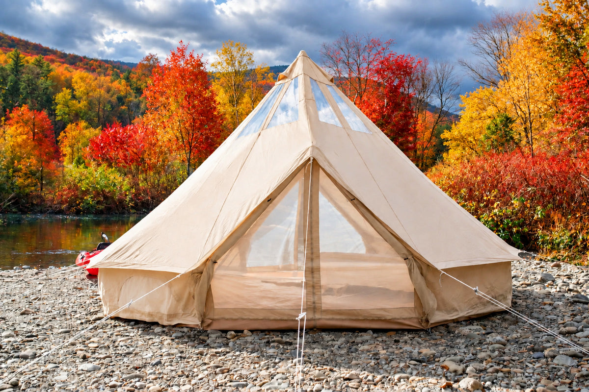 Beige bell tent set up on a rocky area with a forest and mountain backdrop