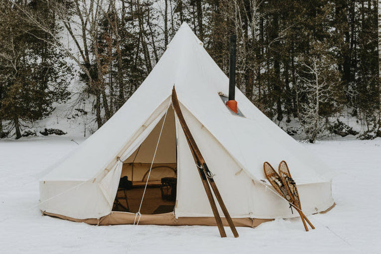 White tent with skis in front on a snowy landscape