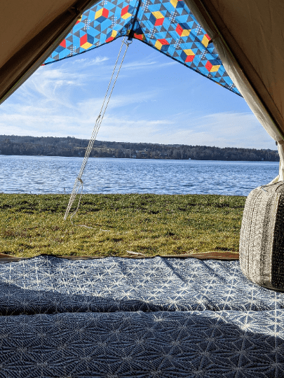 View from inside a tent looking out over a lake with a colorful canopy.