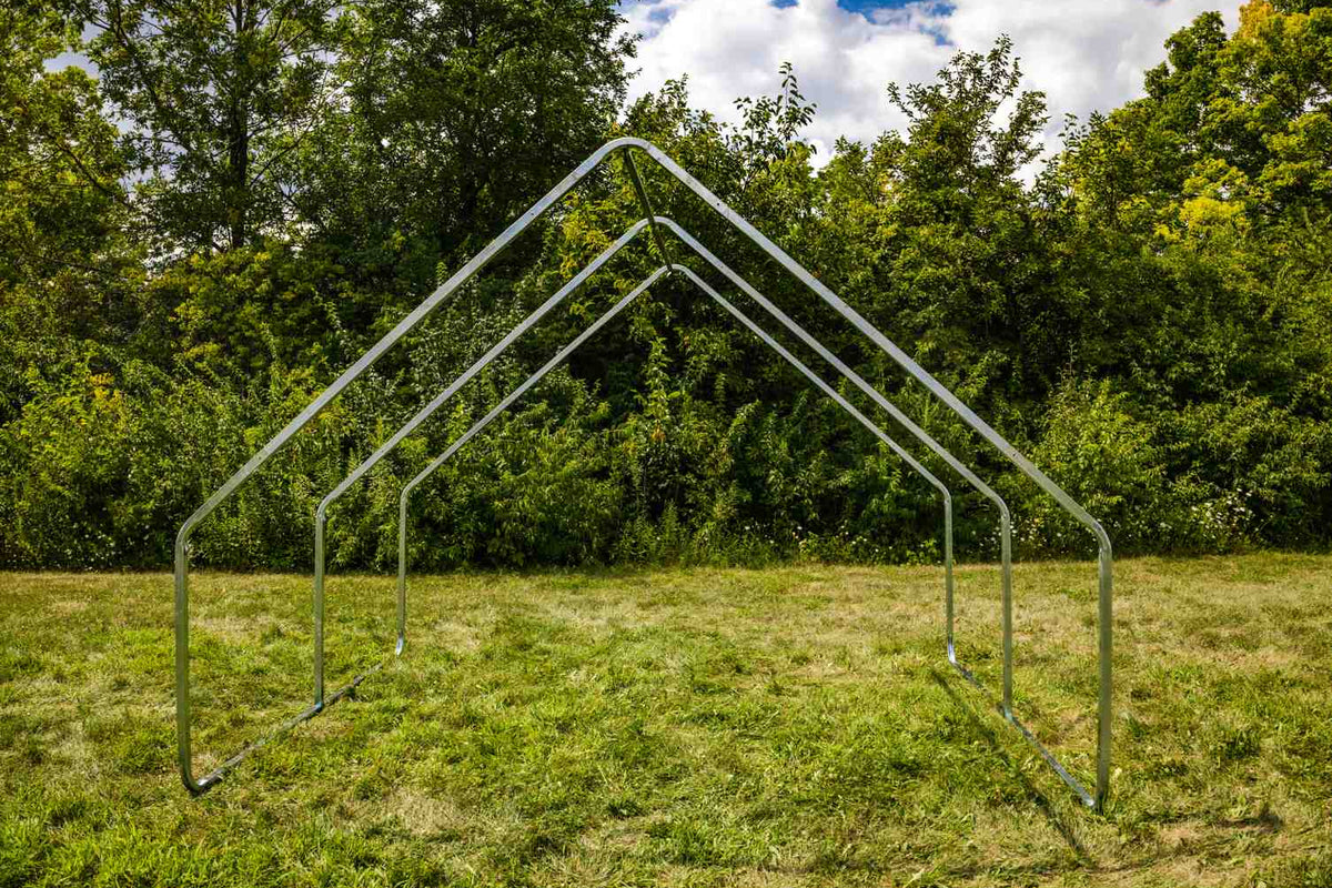 Metal frame structure on a grassy field with trees in the background