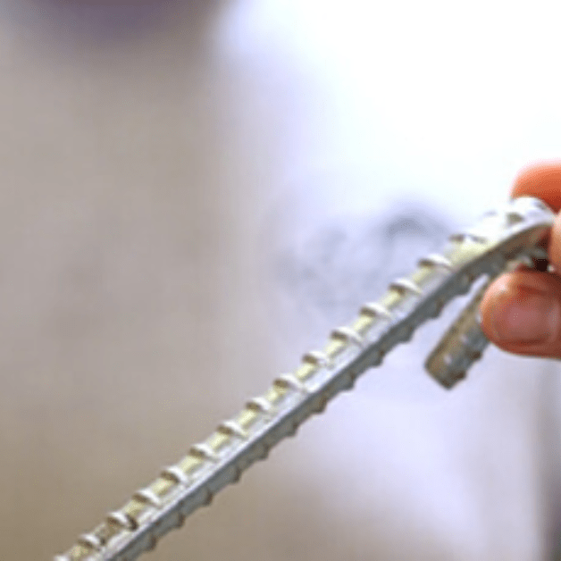 Close-up of a hand holding a tent stake with a blurred background