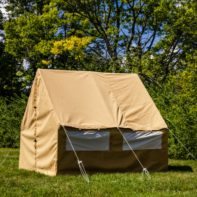 Beige canvas wall tent set up outdoors with trees in the background