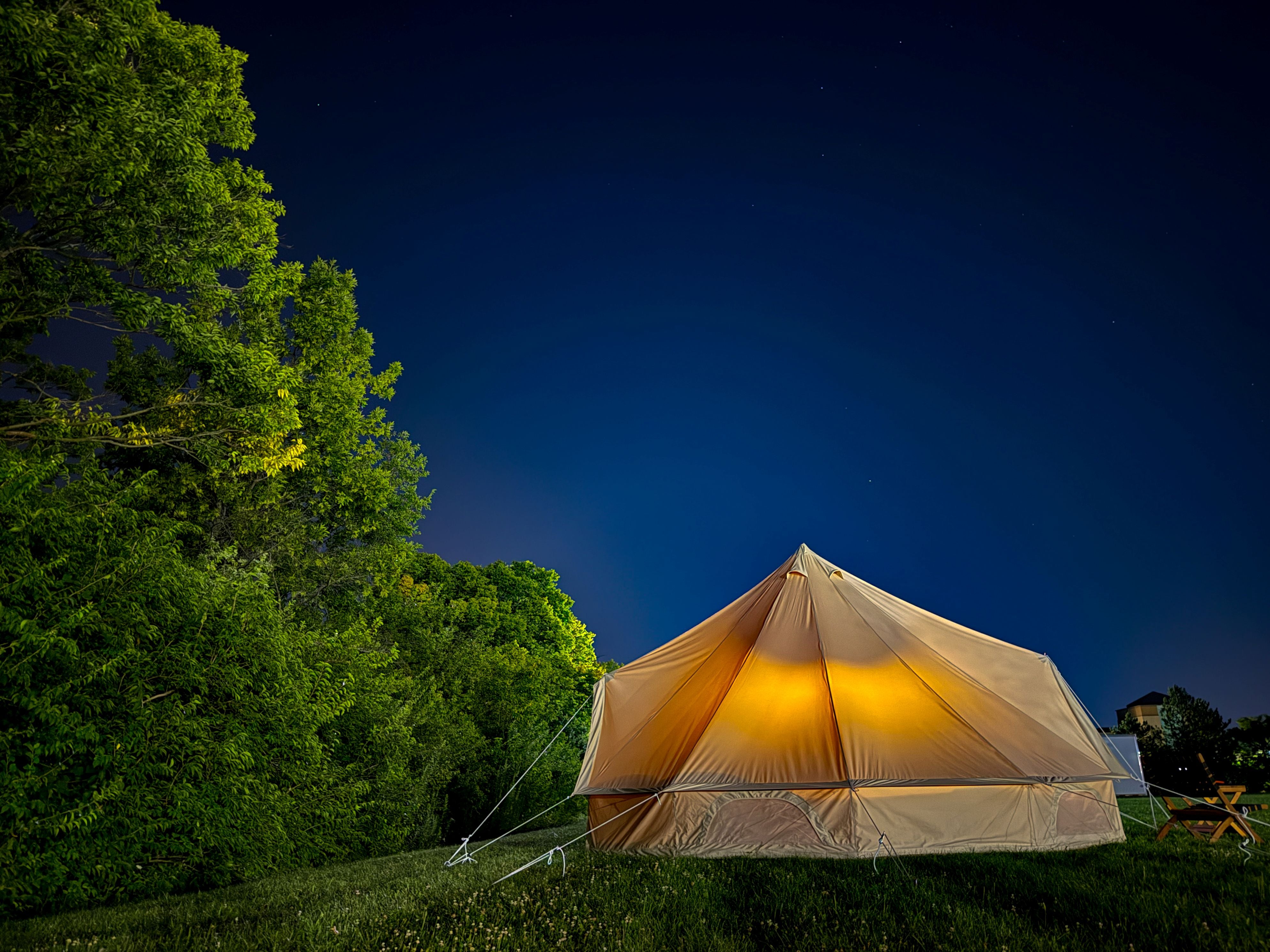 Camping tent illuminated at night in a forest setting