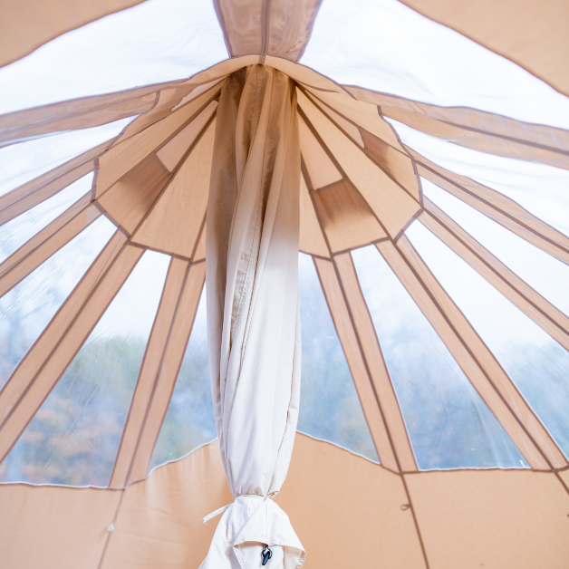 Close-up of a beige tent with a white curtain against a blue sky.