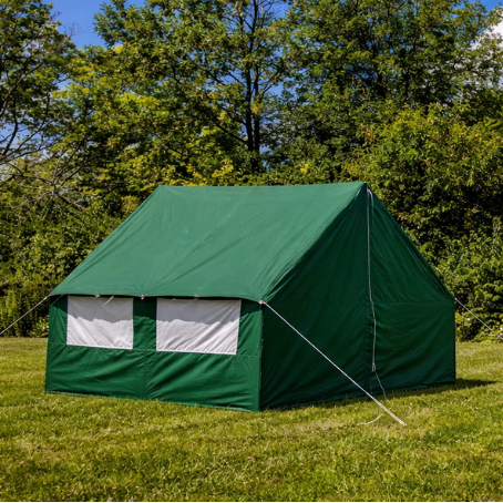 Green wall tent in a grassy area with trees and blue sky