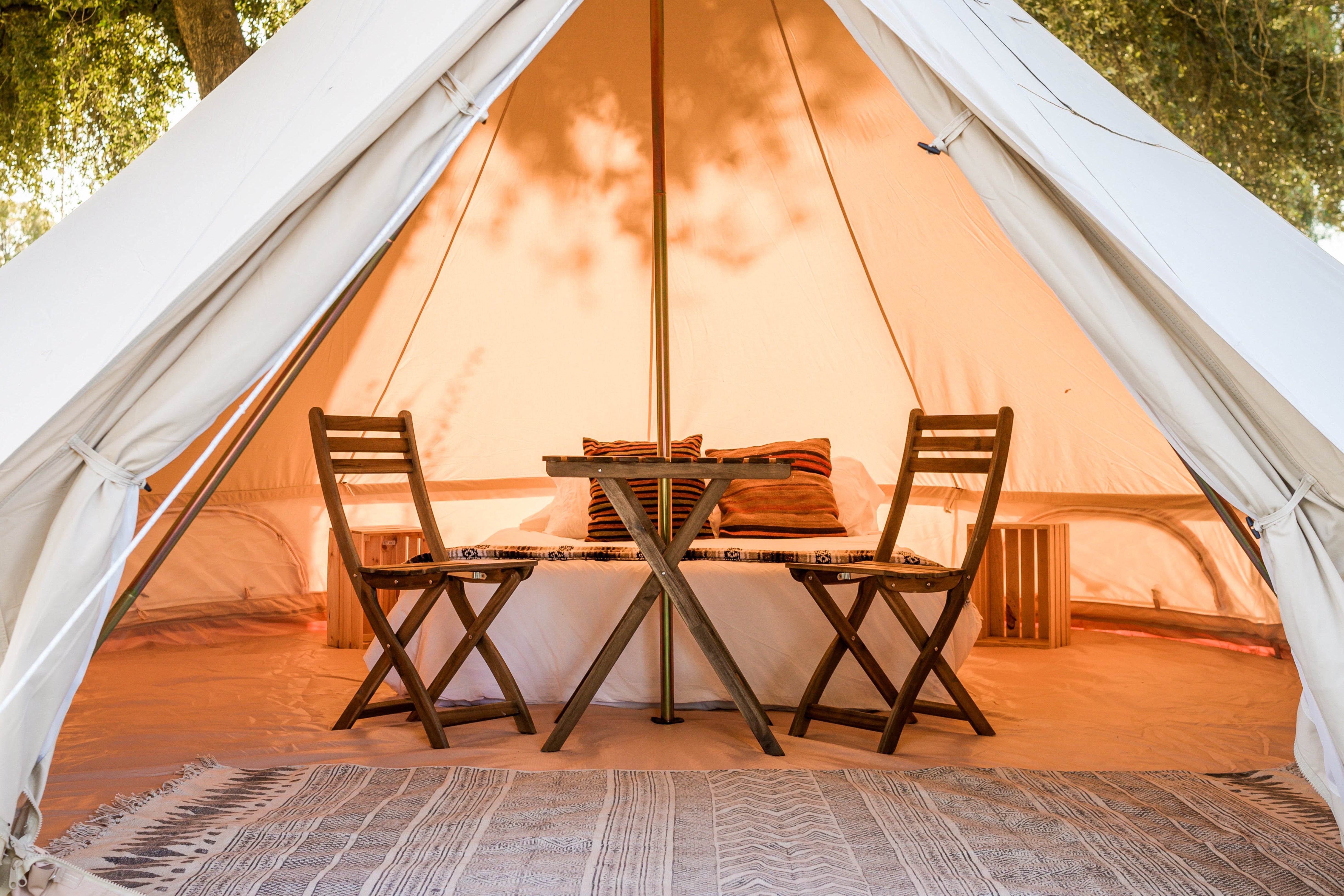 Bell tent with wooden table and chairs in a natural setting
