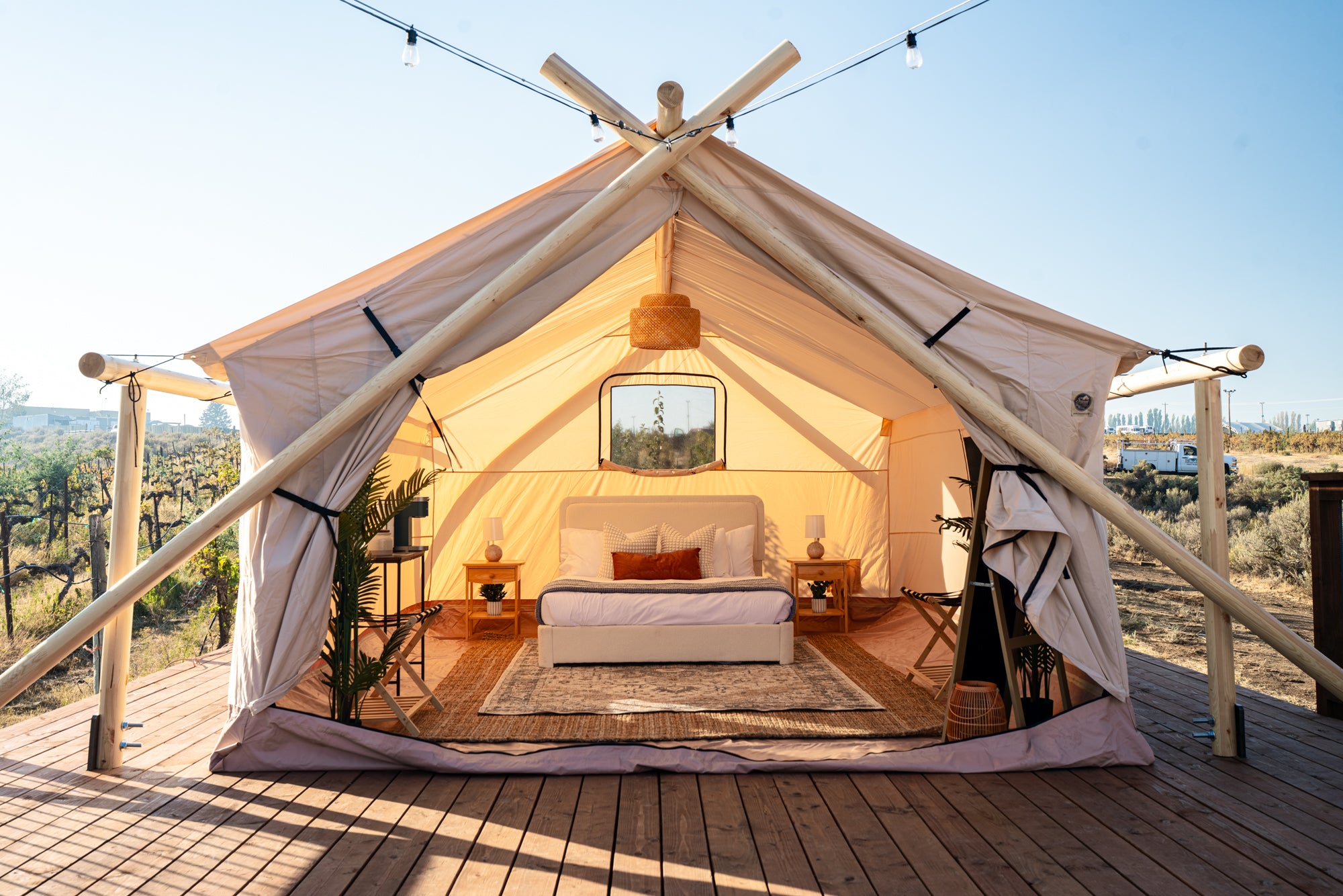 Glamping tent with interior view on a wooden deck, surrounded by nature.