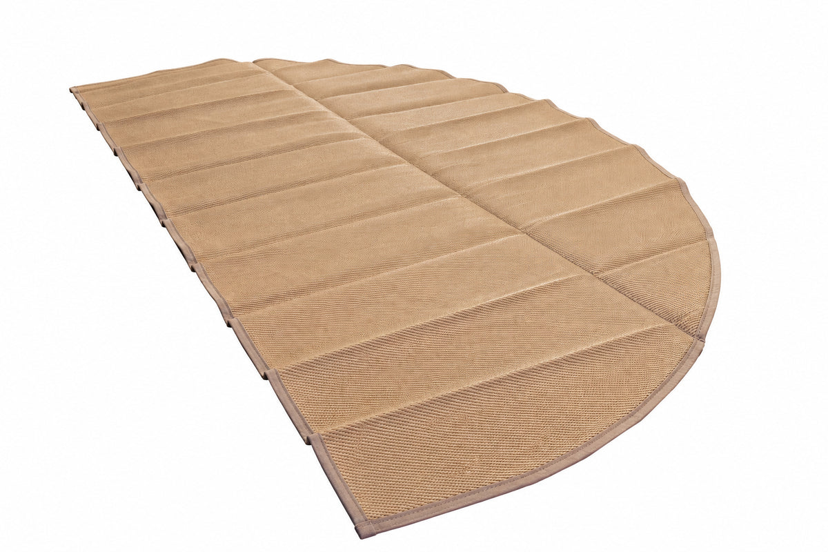 A large tan segmented fabric mat or pad laid out on a glossy green floor in an industrial workshop setting.
