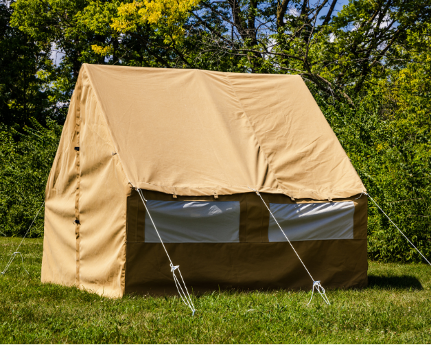 Beige canvas wall tent set up outdoors with trees in the background