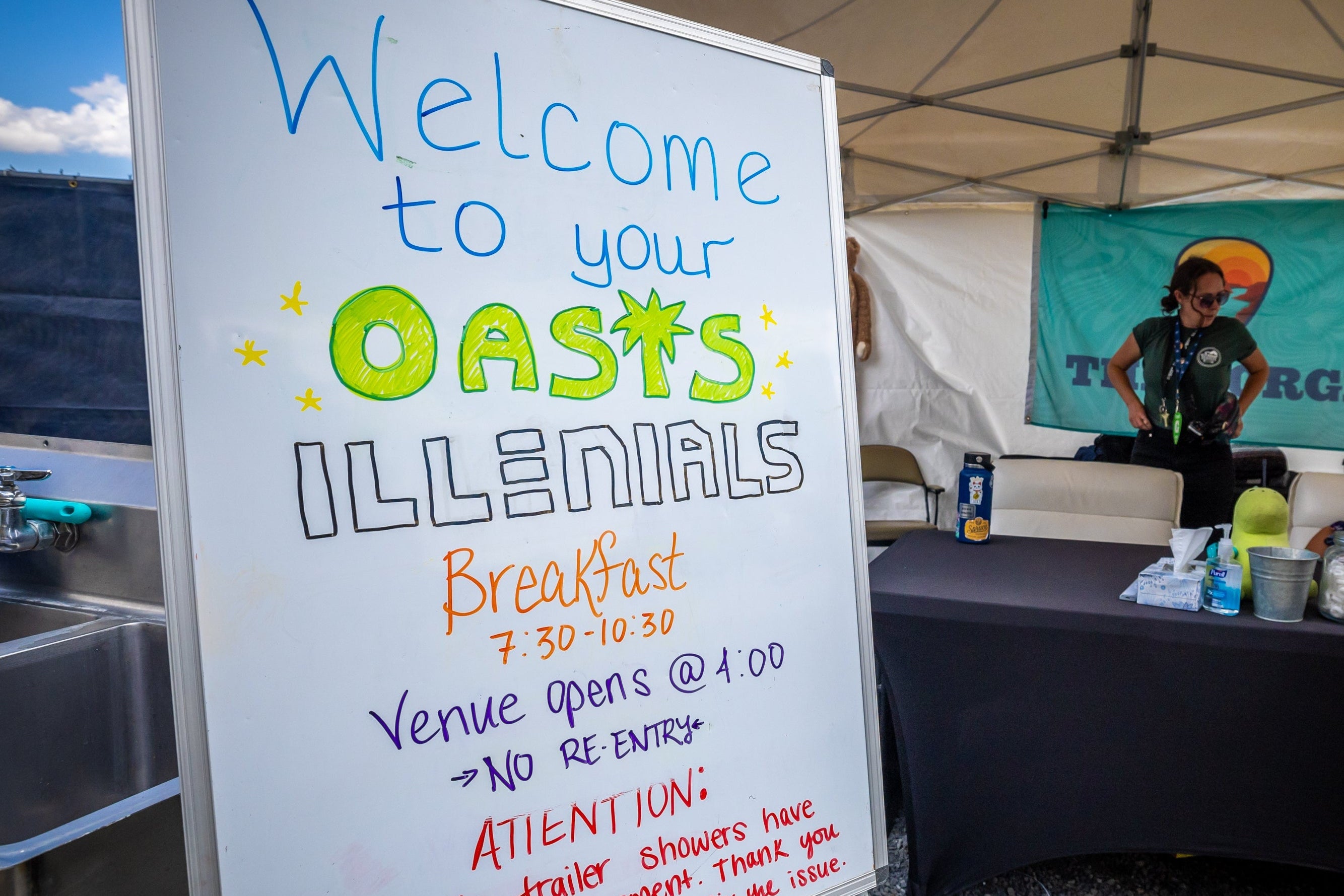 Welcome sign for 'Oases Illenials' event with a person in a red shirt standing nearby.
