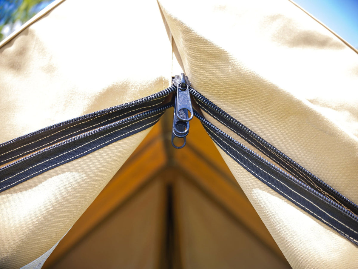 Close-up of a beige tent with a zipper, showing the corner detail.