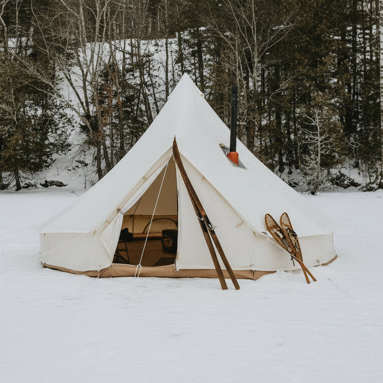 White tent with skis in front on a snowy landscape