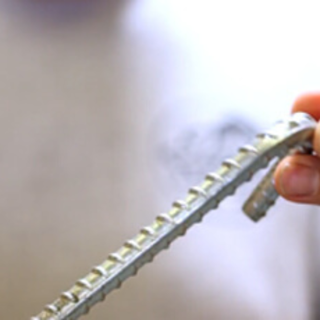 Close-up of a hand holding a tent stake with a blurred background