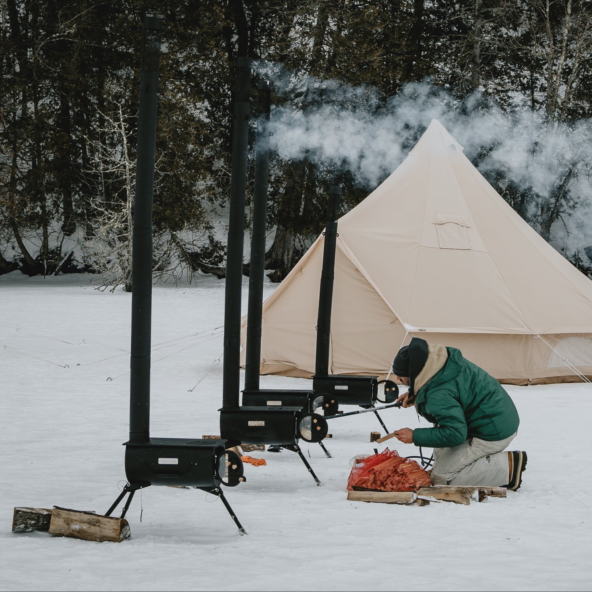 Person camping in a snowy landscape with a tent and portable stove.