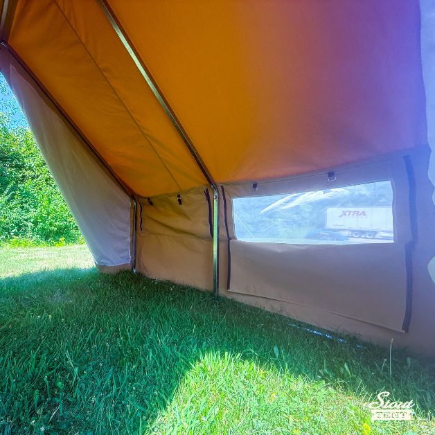 Interior view of a tan canvas wall tent showing the window and light filtering through.