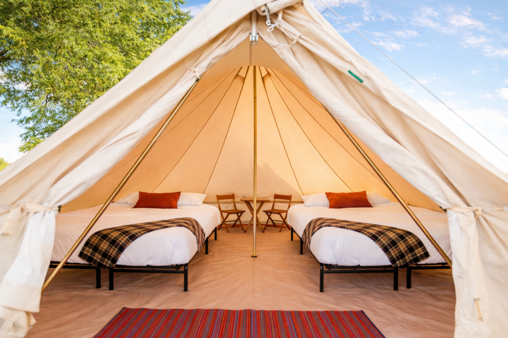 Interior of a luxury Stout Bell Tent at a high-traffic event featuring two twin beds and premium glamping decor.